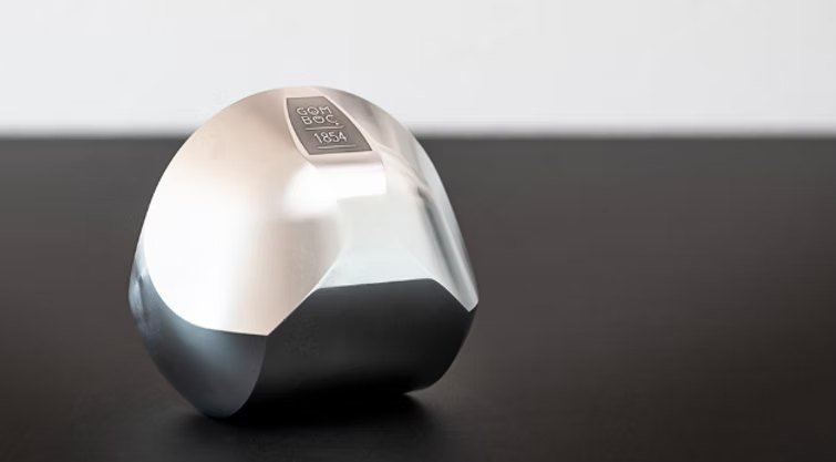 A polished metal Gömböc resting on a table.